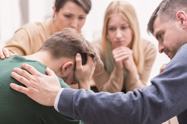 Personnes qui entourent un homme après un deuil au travail.